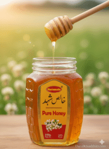 Close-up of golden, thick Pure Honey being drizzled from a wooden dipper into a small glass jar